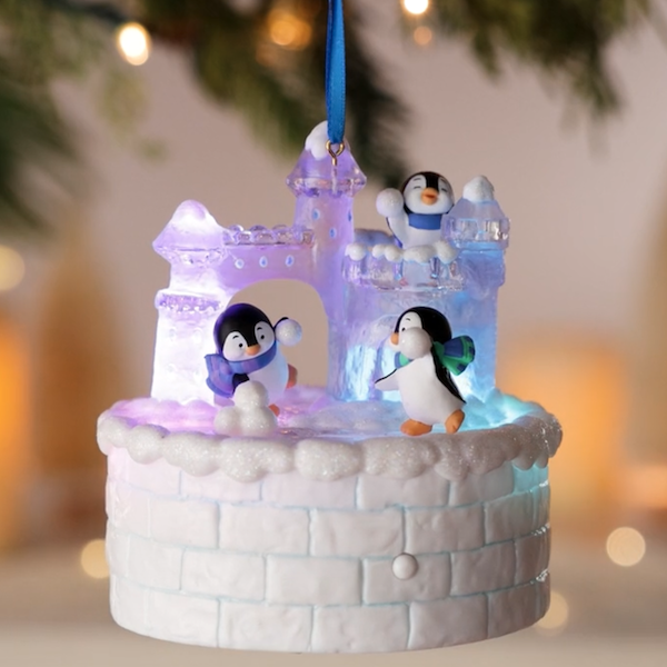 A Keepsake ornament featuring three playful penguins having a snowball fight in a fort made of snow and ice.